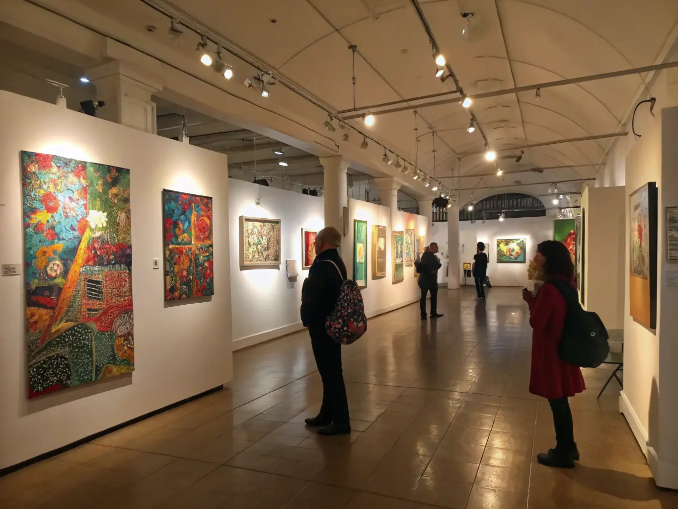 A photograph of a well-attended exhibition showcasing Denise Ferrier's artwork, with people of diverse ages and backgrounds admiring the pieces. The setting is a modern art gallery with bright lighting and informative displays.